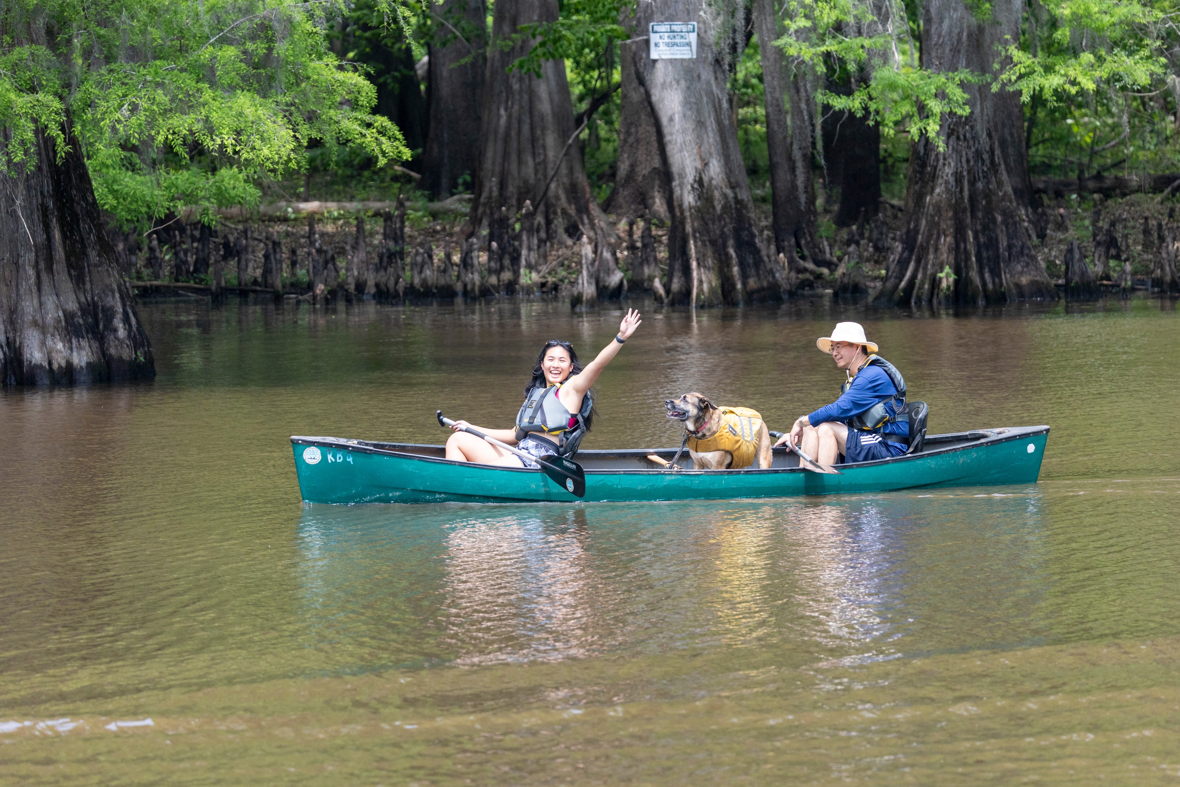 Two paddlers and their dog in a canoe on the cypress bayou
